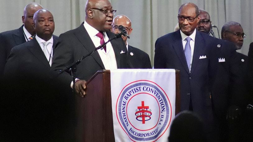 The Rev. Boise Kimber, at podium, president-elect of the National Baptist Convention, USA, addresses the group's annual meeting at the Baltimore Convention Center in Baltimore, Md., on Thursday, Sept. 5, 2024. The Rev. Jerry Young, outgoing NBCUSA president, stands at foreground right. (Adelle M. Banks/RNS via AP)